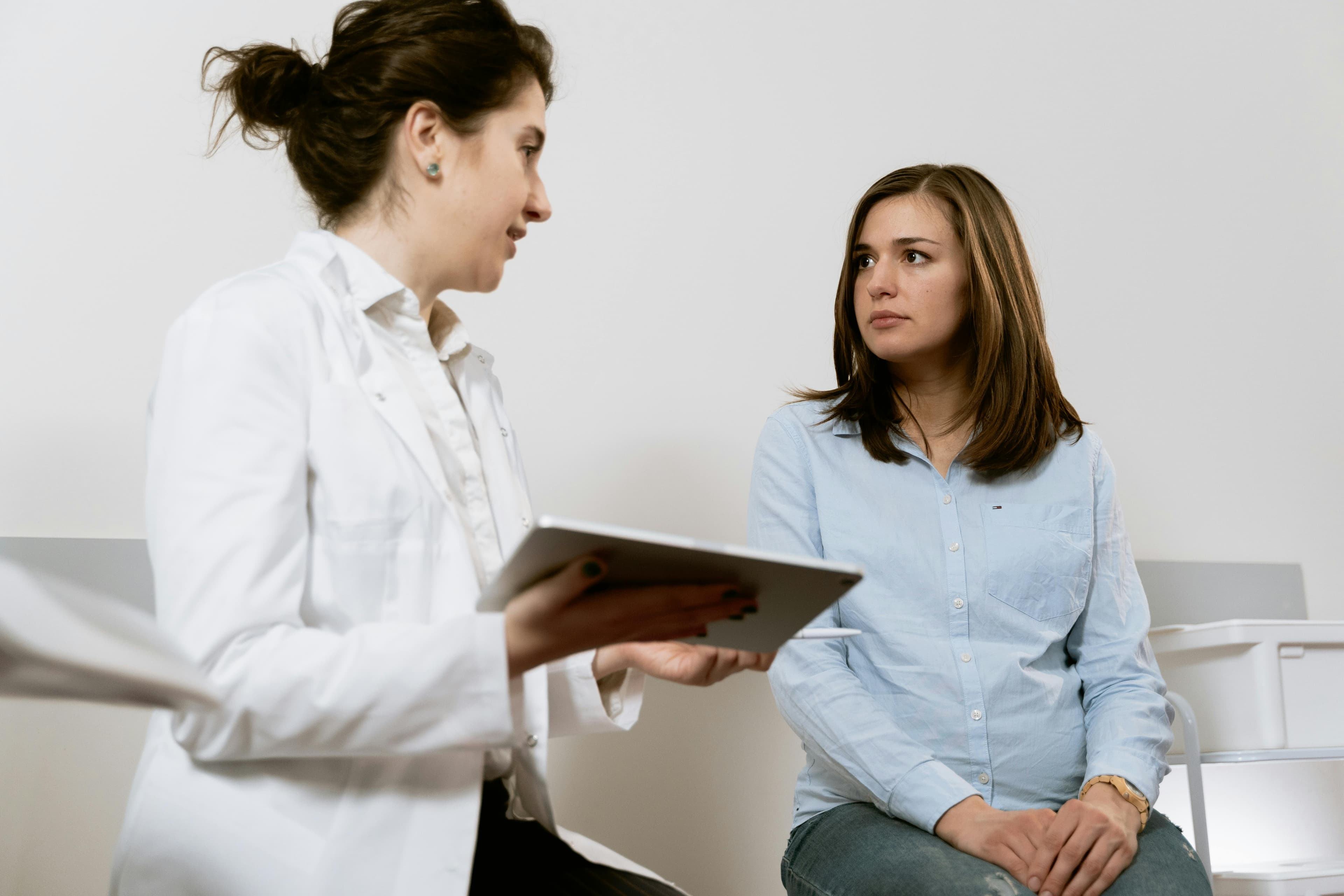 Woman holding GLP-1 medication pen with calendar tracking menstrual cycle in background